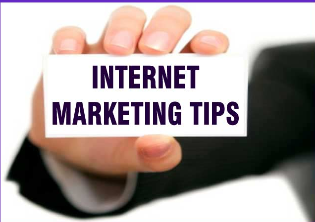 A person in a dark suit holds a card with bold text that reads "INTERNET MARKETING TIPS." The fingers are positioned at the top and bottom edges of the card.