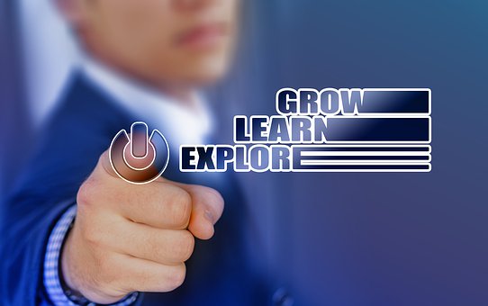A person in a suit points towards the foreground with text overlays that say "Grow," "Learn," and "Explore," next to a power button symbol. The background is a blurry blue gradient.